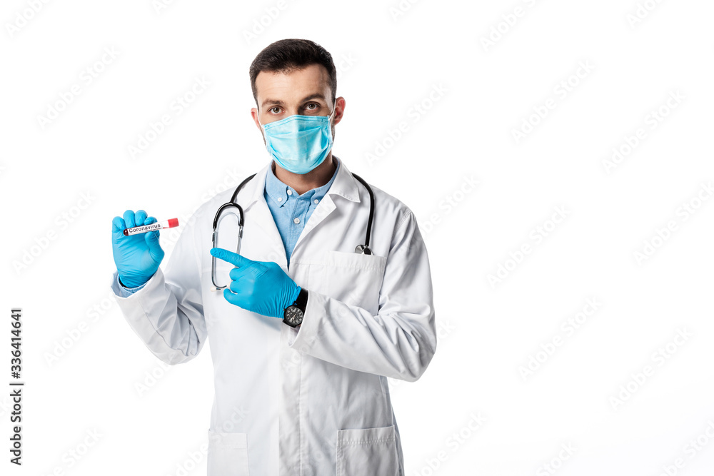 doctor in medical mask and white coat pointing with finger at test tube with sample and coronavirus lettering isolated on white doctor in medical mask and white coat pointing with finger at test tube with sample and coronavirus lettering isolated on white