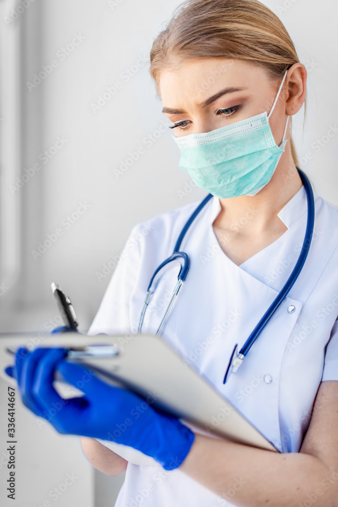 Female doctor in a protective mat writes on a piece of paper Female doctor in a protective mat writes on a piece of paper