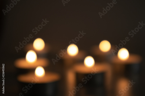 Unfocused burning candles in the darkness of a sad time, sorrow and memory