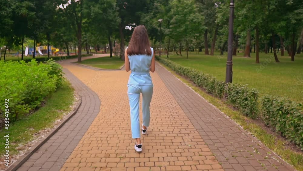 back view woman in casual clothes walking on the street jump for joy holding smartphone in her hand back view woman in casual clothes walking on the street jump for joy holding smartphone in her hand