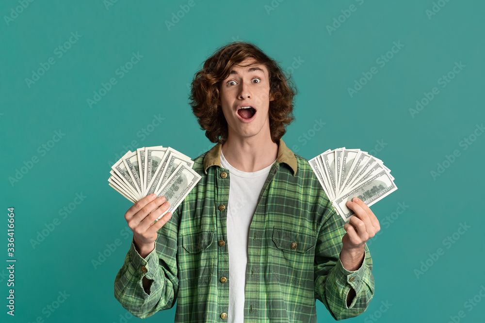Big win. Excited millennial guy holding money, shouting WOW, color background Big win. Excited millennial guy holding money, shouting WOW, color background