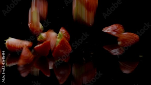 A group of strawberries falling onto black surface photo