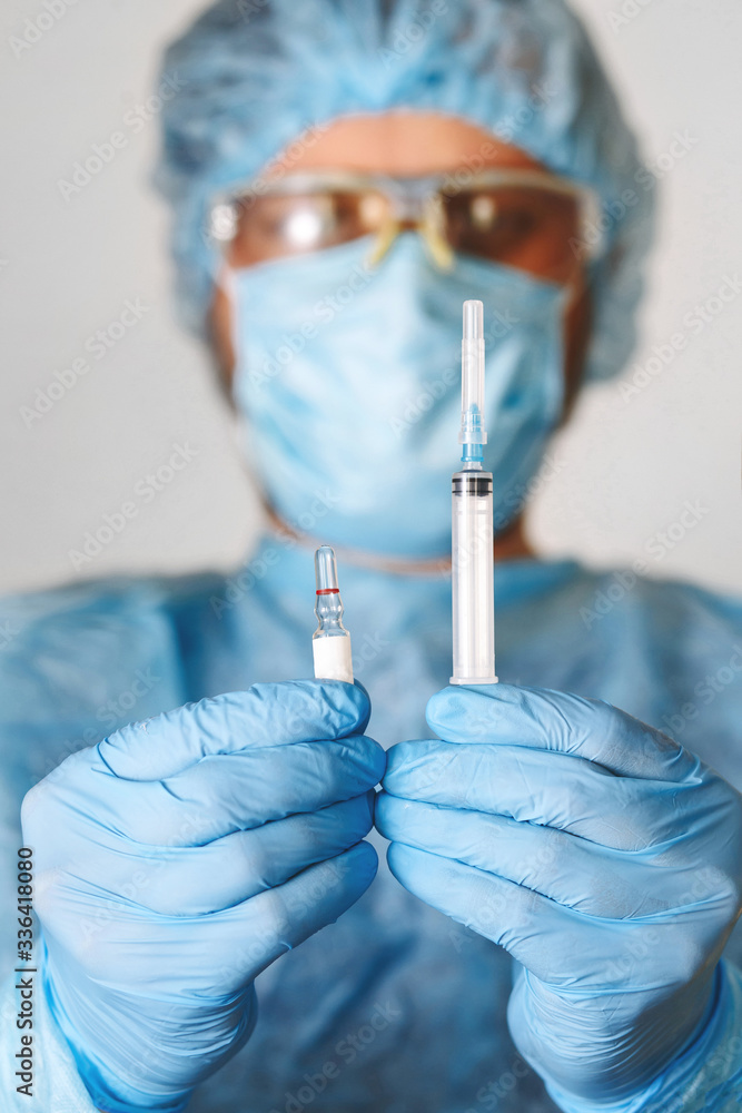 Close up of doctor hand holding vaccine. Medical equipment. A doctor wearing personal protective equipment including mask, goggle, and suit to protect COVID coronavirus infection. Close up of doctor hand holding vaccine. Medical equipment. A doctor wearing personal protective equipment including mask, goggle, and suit to protect COVID coronavirus infection.