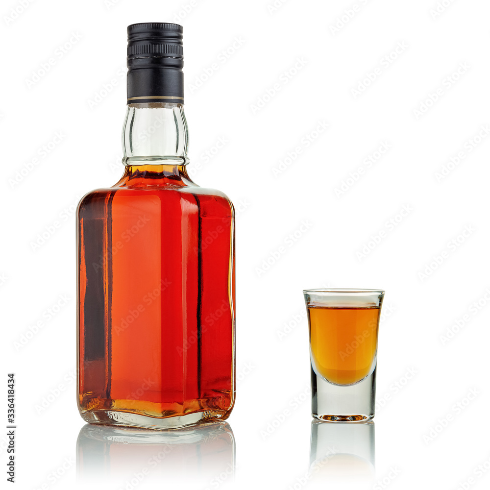 A bottle and a shot glass with alcoholic beverages. A bottle and a shot glass with alcoholic beverages.
