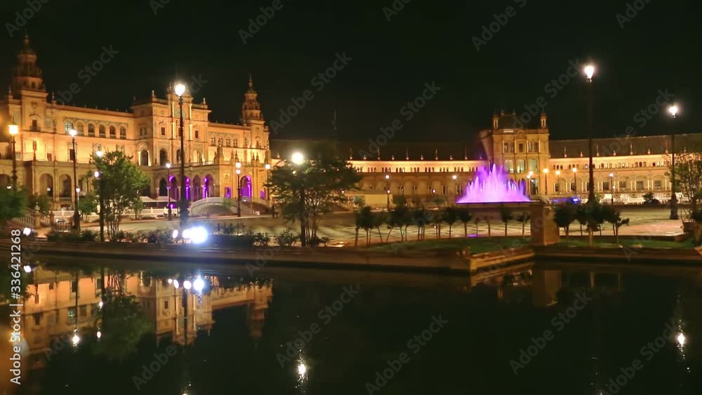 Renaissance building in Plaza de Espana reflects on channel of Guadalquivir river in Seville. Scenic Spain Square in Andalusia, Spain, illuminated at night. Popular tourist attraction.