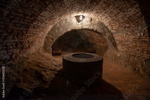 Photos Dark corridors of old time castle dungeon light with few lamps and well