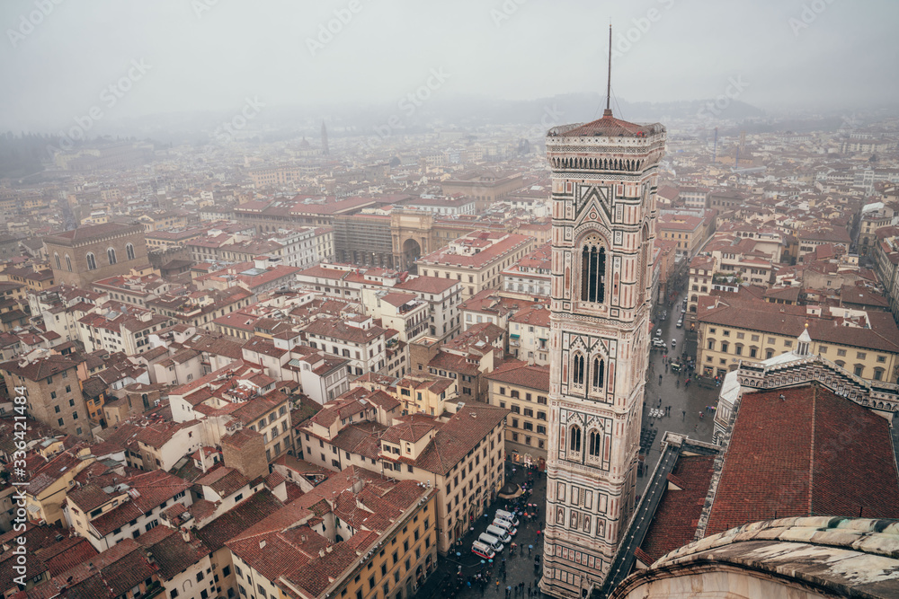 view of Giotto's tower and the arch of Piazza della Repubblica from the dome of Florence's cathedral on a foggy day. Centre of Florence, Italy.