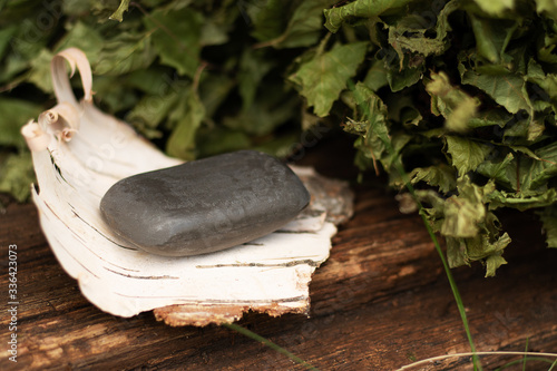 Tar soap lies on birch bark. Aged wooden background, birch leaves. Eco-friendly body care, disease protection. Personal hygiene