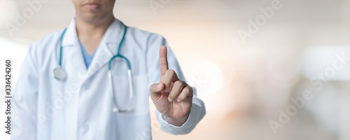 Medical doctor with pointing finger on copy space or virtual screen technology on blur hospital background