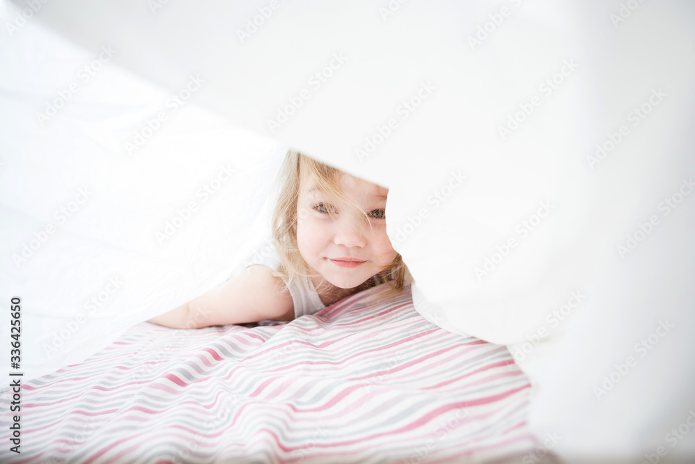 kid girl playing under blanket on bed. kid girl playing under blanket on bed.