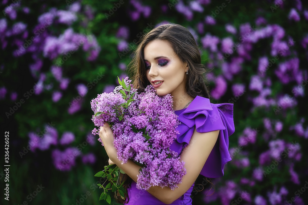 beautiful young girl in a purple dress holds in her hands a bouquet of lilac in bloom lilac. beautiful young girl in a purple dress holds in her hands a bouquet of lilac in bloom lilac.