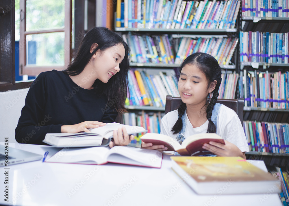 Two Asian girl students reading books and using notebook in the library. Two Asian girl students reading books and using notebook in the library.