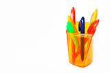 multi-colored plastic stationery pens in an orange a glass
