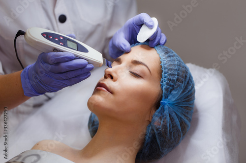 Ultrasonic peeling. Young woman on face cleaning procedure in a beauty salon. Close up