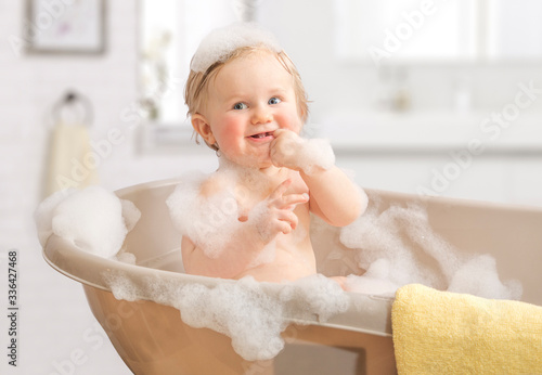 Child washing in a bathroom in foam.