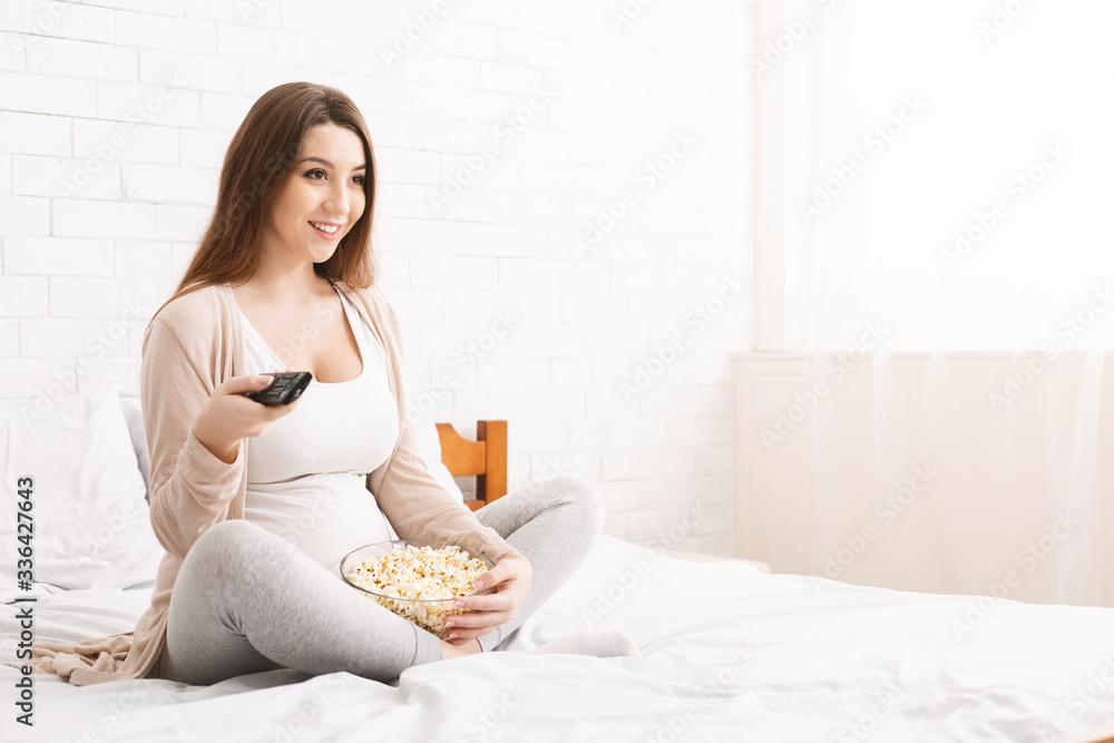 Pregnant woman watching tv at home with popcorn Pregnant woman watching tv at home with popcorn
