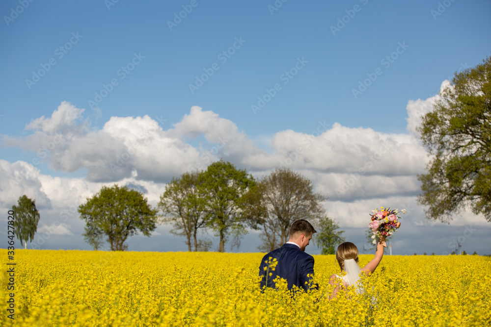 Beautiful young wedding couple posing outdoor in yellow field