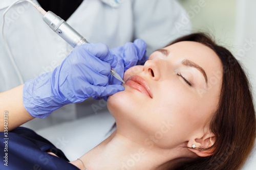 Young woman having permanent makeup on lips in beautician salon. Close up