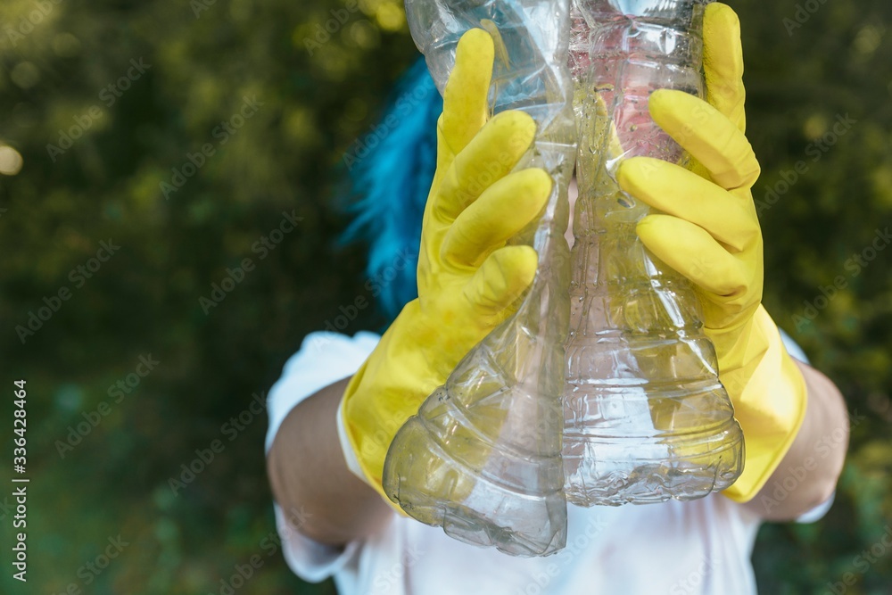 Female wearing gloves holding recyclable plastic bottles plastic