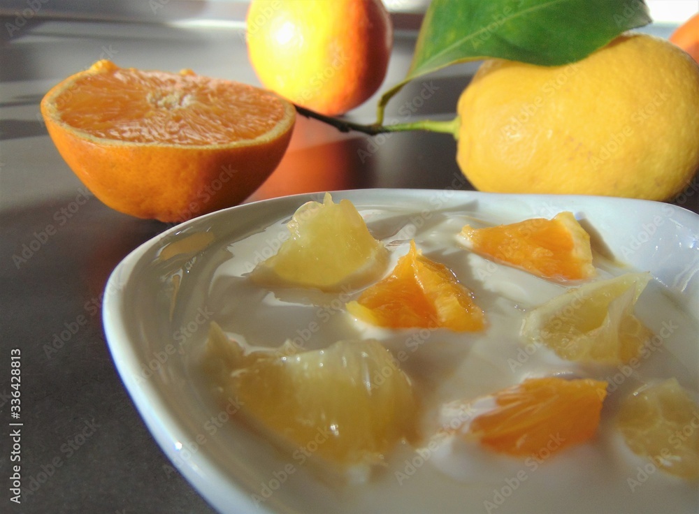 Yoghurt with citrus fruits in a bowl. Sour cream, yogurt with fresh orange and lemon, close up. Yoghurt with citrus fruits in a bowl. Sour cream, yogurt with fresh orange and lemon, close up.