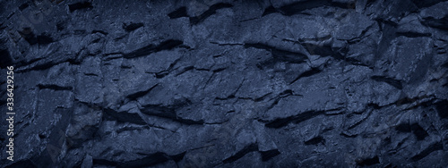 Abstract dark blue background. Toned rock texture. Banner with monochrome stone texture. Fragment of a mountain close-up.