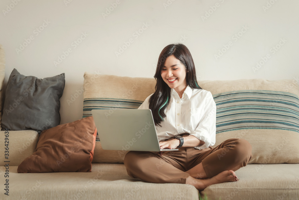 Happy young asian woman with a laptop sitting on the sofa at home. Happy young asian woman with a laptop sitting on the sofa at home.