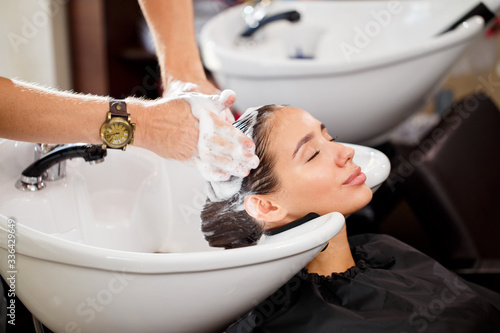Beautiful brunette washes hair in a beauty salon