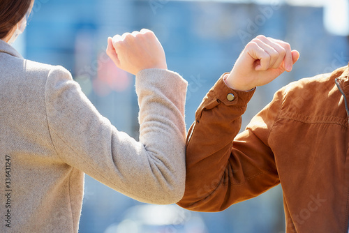 A close-up photo of elbow bumping. Elbow greeting to avoid the spread of coronavirus (COVID-19). Man and woman meet with bare hands. Instead of greeting with a hug or handshake, they bump elbows. photo