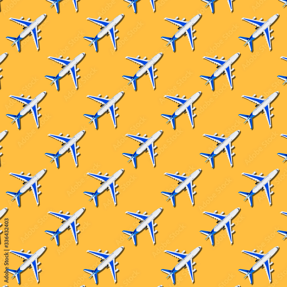 Pattern, seamless model airplane texture, plane on yellow background. Summer travel or vacation pattern. Creative composition made with passenger plane on pastel yellow background. Top view, flat lay. Pattern, seamless model airplane texture, plane on yellow background. Summer travel or vacation pattern. Creative composition made with passenger plane on pastel yellow background. Top view, flat lay.