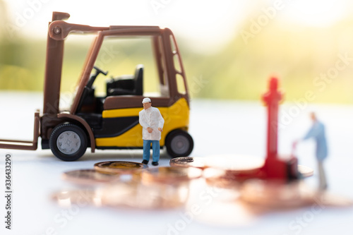 Miniature people: Worker use pallet truck with stack of coins. Image use for background business concept.