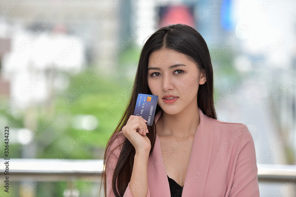 Asian girl in pink suit send a sweet smile to a hand holding a credit card Asian girl in pink suit send a sweet smile to a hand holding a credit card
