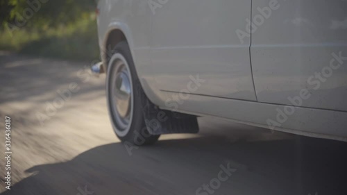 Wheels of old white soviet vintage car driving on dirt road