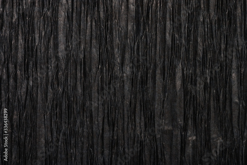 Background of black pressed corrugated paper with a vertical texture taken close up