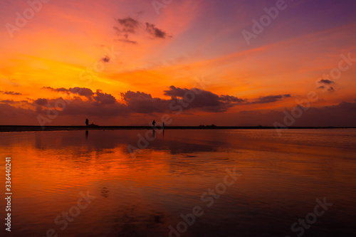 Burning bright sky during sunset on a tropical beach. Sunset during the exodus  the strength of people walking on water