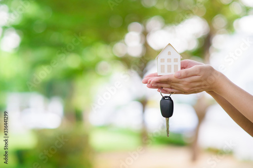 Woman is holding house and car key on green © tonefotografia