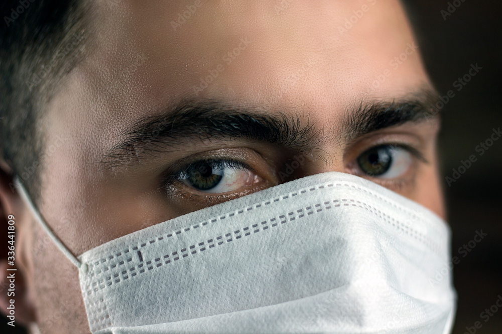 young man in medical mask on a dark background young man in medical mask on a dark background