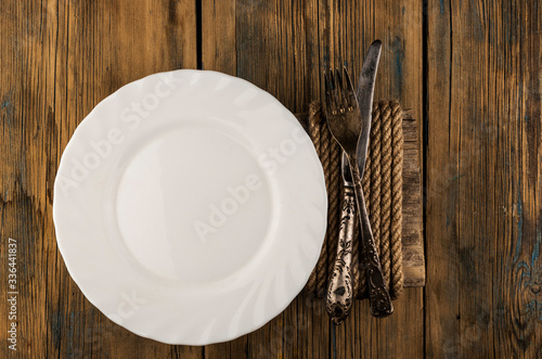 Empty plate, knife, fork on wood table background with text space