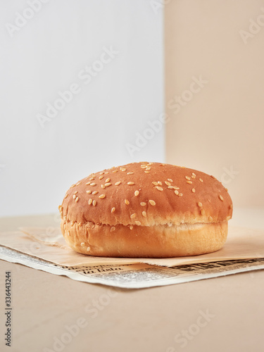 pan de hamburguesa con semillas de sésamo solo sin nada vista frontal sobre papel, fondo blanco y crema photo