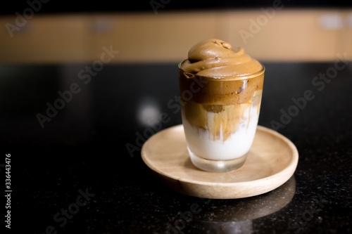 Iced Dalgona Coffee, a trendy korean style  cremy whipped coffee on fresh milk, on wooden tray