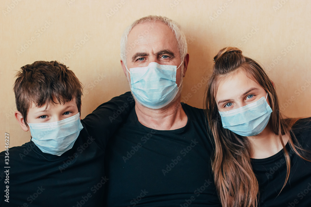 grandfather in face mask with grandchildren look at the camera on yellow background and in diplomacy think about the consequences of coronavirus.Isolated during quarantine due to coronavirus epidemic.