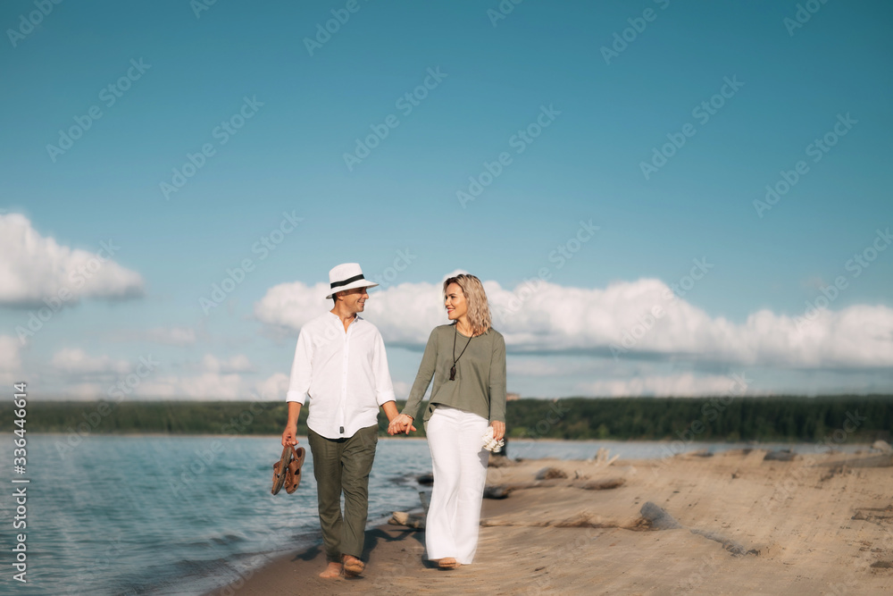 Woman and man walk on the beach in sunny weather