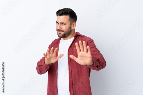 Young handsome man with beard wearing a corduroy jacket over isolated white background nervous stretching hands to the front