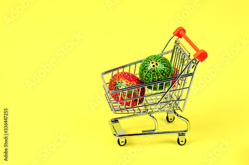 Hand-painted Easter eggs in a supermarket trolley on a yellow background