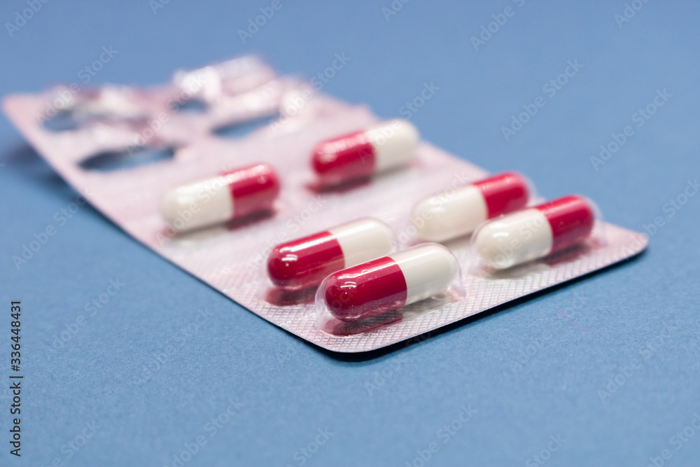 Opened packaging with capsules on a blue background. Isolated. Side view. Opened packaging with capsules on a blue background. Isolated. Side view.