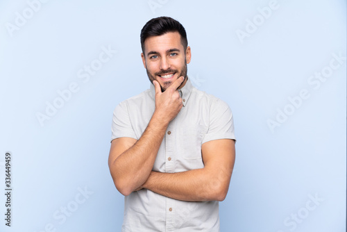 Young handsome man with beard over isolated blue background laughing