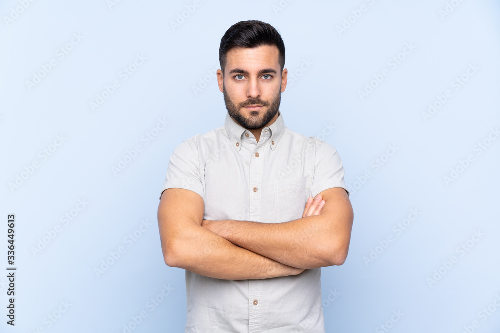 Young handsome man with beard over isolated blue background keeping arms crossed Young handsome man with beard over isolated blue background keeping arms crossed
