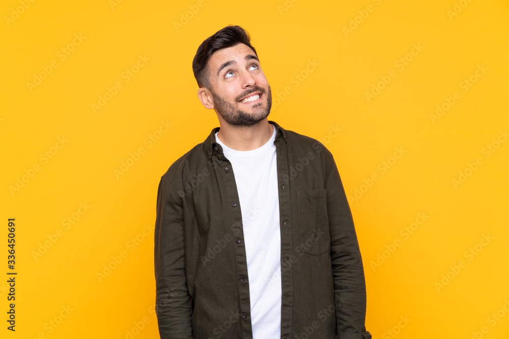 Man over isolated yellow background laughing and looking up Man over isolated yellow background laughing and looking up