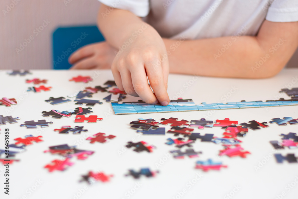 The child collects a puzzle. The development of fine motor skills and intelligence. Children's hands during the game. Home leisure. The child collects a puzzle. The development of fine motor skills and intelligence. Children's hands during the game. Home leisure.