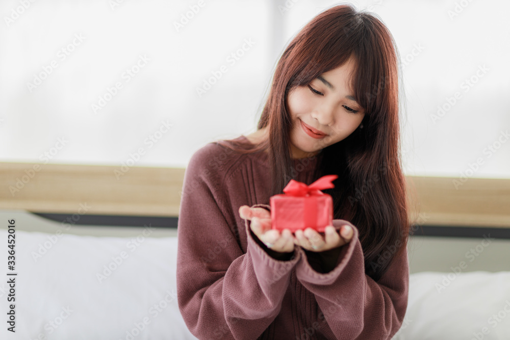 Asian beautifull woman holding red gift box and happiness in her bed room. Stay at home. Asian beautifull woman holding red gift box and happiness in her bed room. Stay at home.
