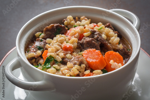 Homemade beef and barley soup. Gray background. Close-up.